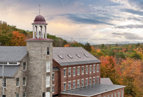 Beautiful sky and colorful autumn scene in historic town of Harrisville, New Hampshire. Old bell tower and preserved textile mill buildings built of granite and brick in 19th century. photo