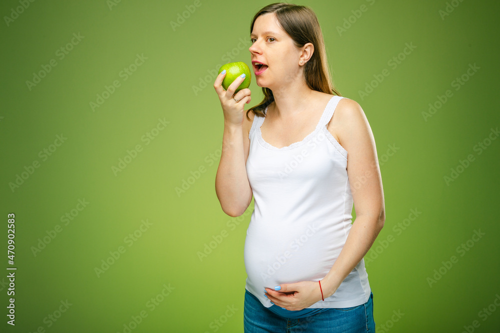 Pregnant woman eating a green apple, healthy eating when you are pregnant for a healthy baby. Wellbeing for vegetarians while they carry a baby. Pregnant woman eating a green apple, healthy eating when you are pregnant for a healthy baby. Wellbeing for vegetarians while they carry a baby.