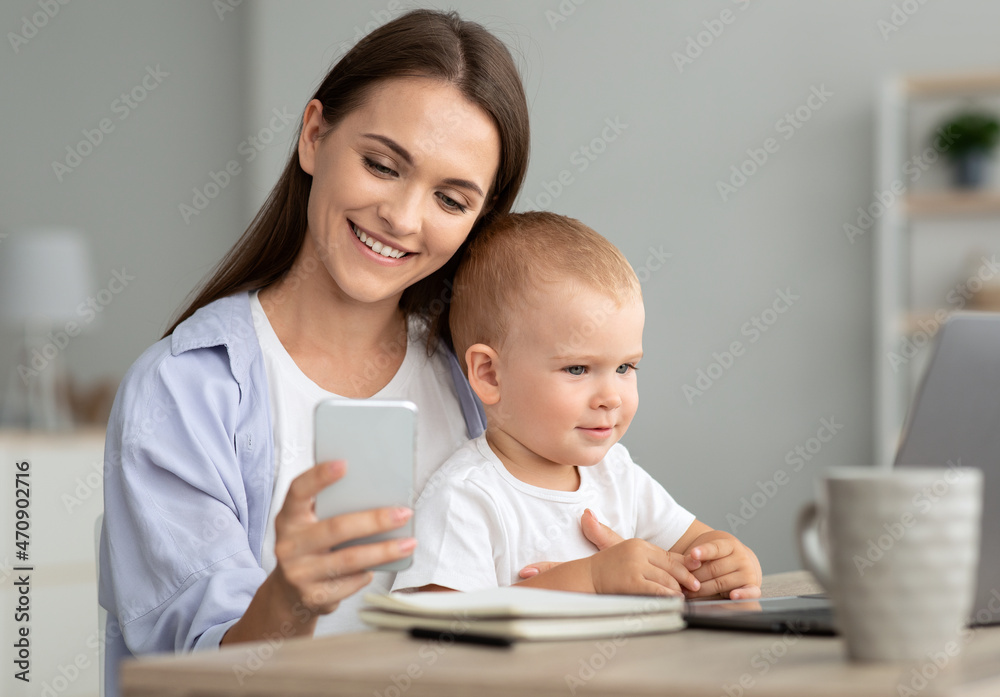Young Mother Messaging On Smartphone While Spending Time With Baby At Home Young Mother Messaging On Smartphone While Spending Time With Baby At Home