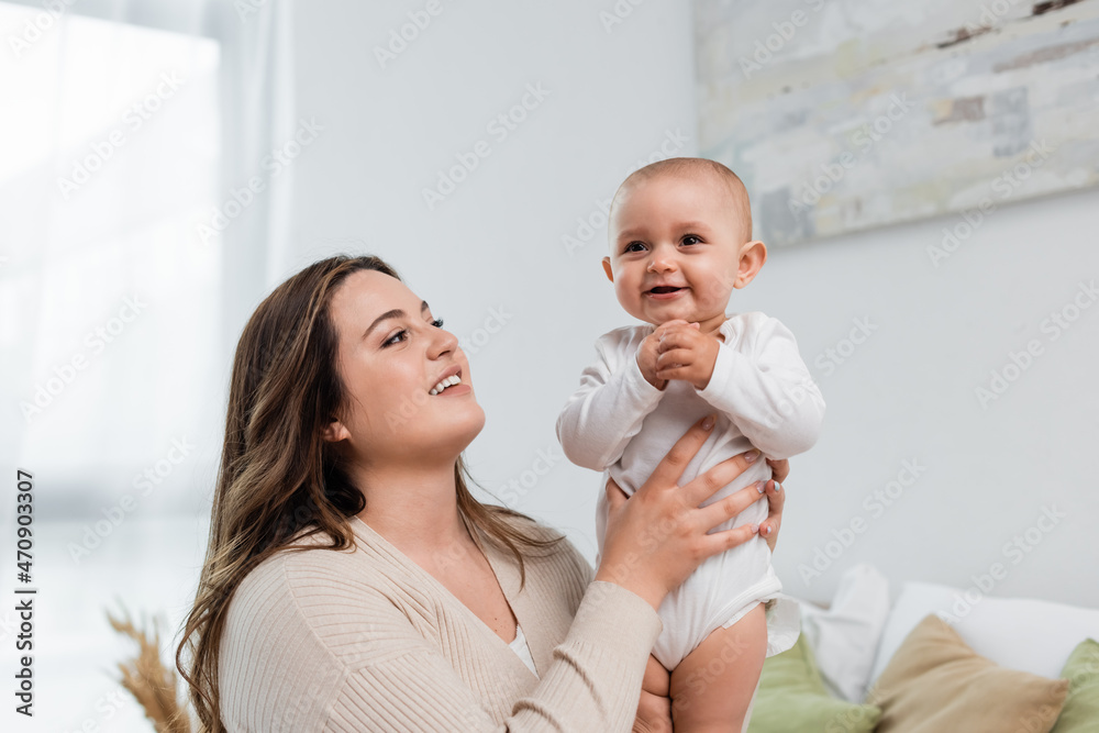 Young plus size woman holding smiling baby daughter at home. Young plus size woman holding smiling baby daughter at home.
