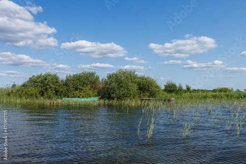 Old rural wooden  fishing boat moored in the shallow waters of the lake