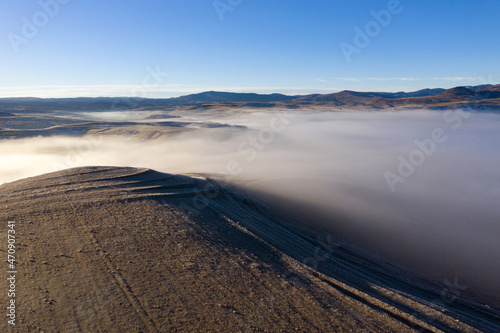 Flying over hills in mystic foggy winter morning. Aerial view