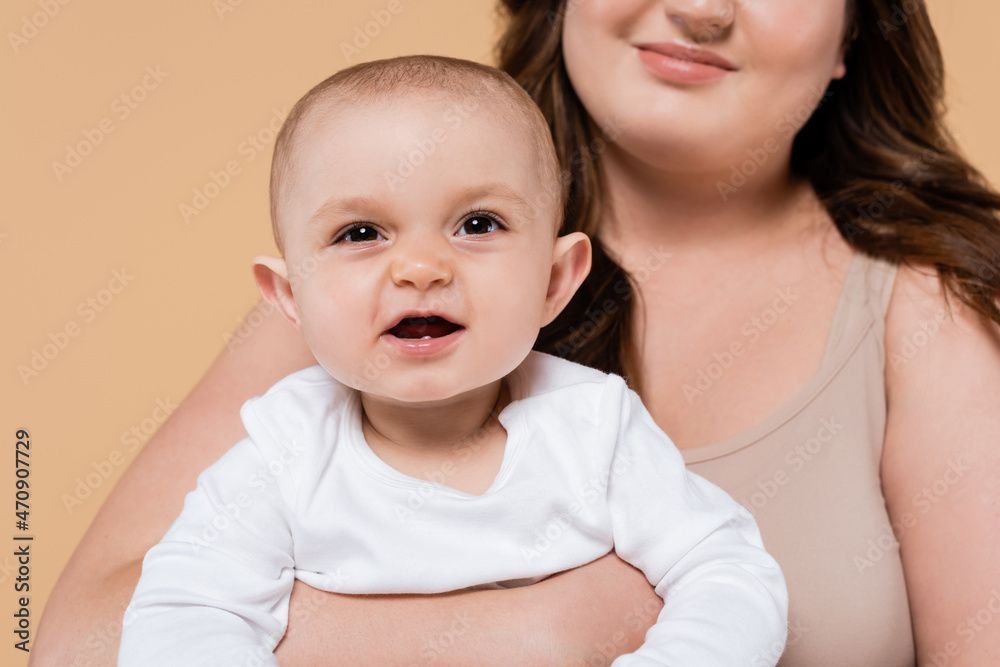 Smiling brunette mother holding baby daughter isolated on beige. Smiling brunette mother holding baby daughter isolated on beige.