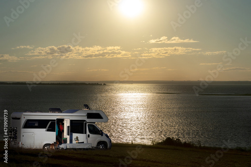 Autotourism. Camper overnight on the river bank. Evening, the sun sets over the horizon. Selective focus. © ROMAN DZIUBALO