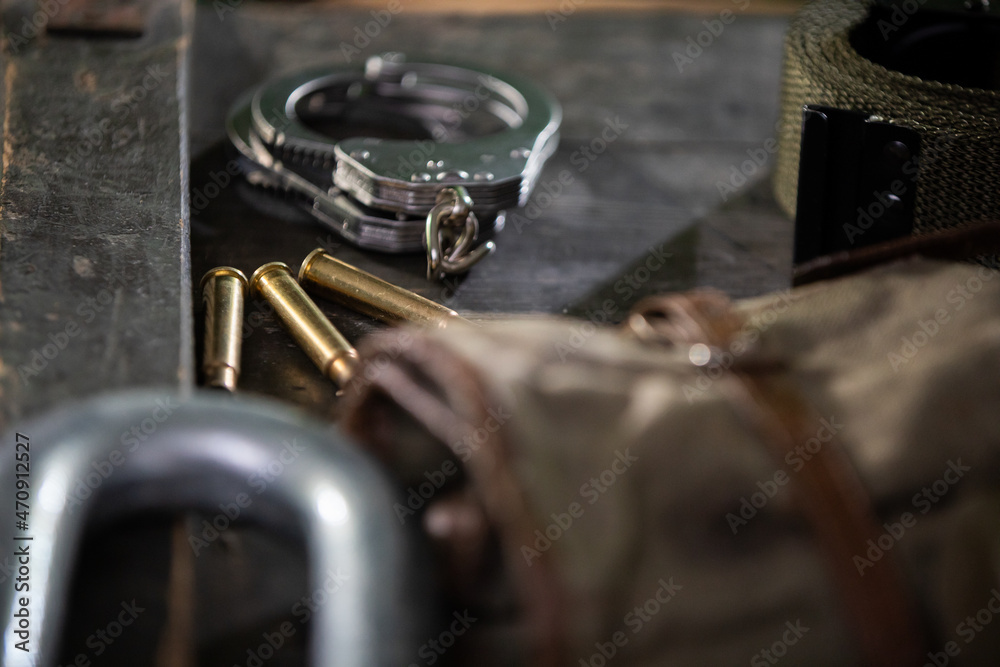Fototapeta premium On the crate are eating handcuffs three empty rifle cartridges and a military belt.