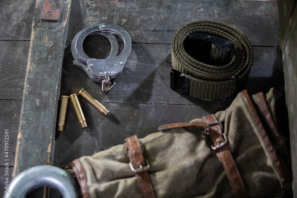 Obraz premium On the crate are eating handcuffs three empty rifle cartridges and a military belt.
