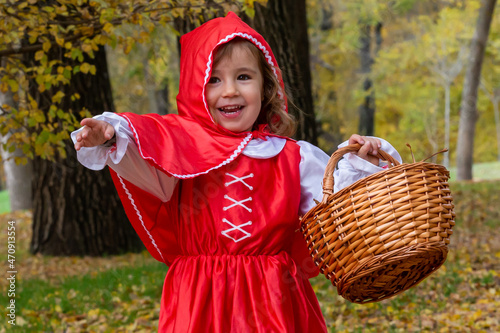 Little Red Riding Hood walks through the woods with her little basket on the way to her grandmother's house. Girl with costume