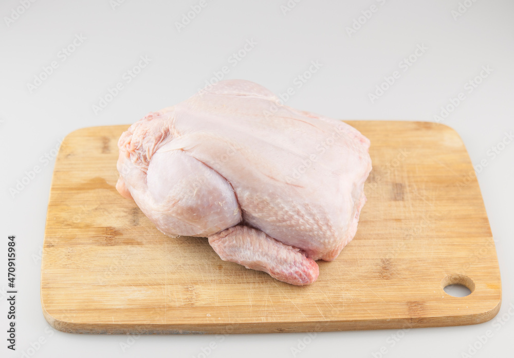 Frozen chicken carcass on a wooden chopping board Frozen chicken carcass on a wooden chopping board