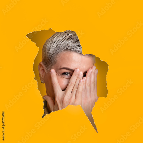 Shy curious woman looking through paper hole