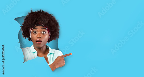 Surprised shocked black woman peeping through paper hole photo