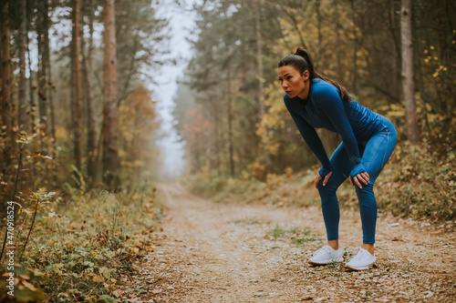Young woman take a break during outdoor exercise on the forest trail at autumn