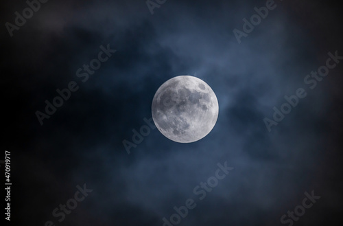 Full moon against the black cloudy night sky