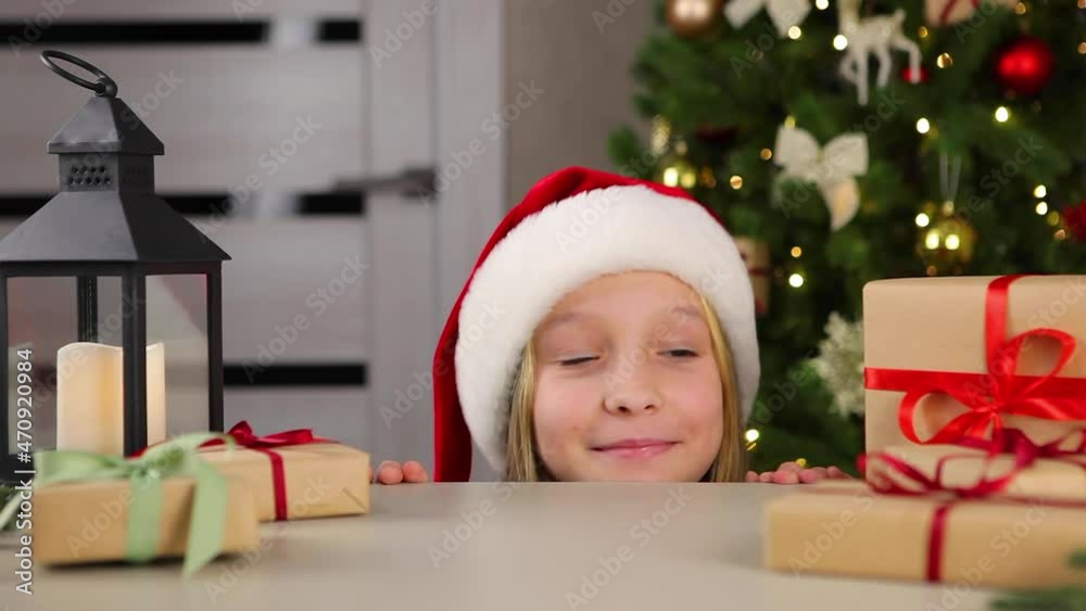 The girl looks at the table where the Christmas gifts lie The girl looks at the table where the Christmas gifts lie