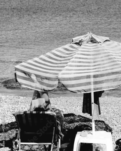 person reading on the beach under a sun umbrella photo