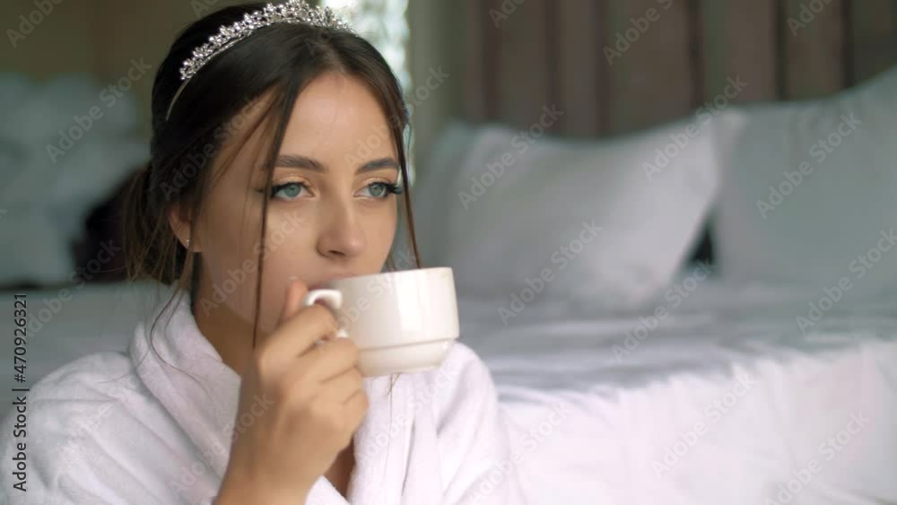 Very beautiful girl with a crown on her head drinking her morning coffee in the bedroom. Close-up Very beautiful girl with a crown on her head drinking her morning coffee in the bedroom. Close-up
