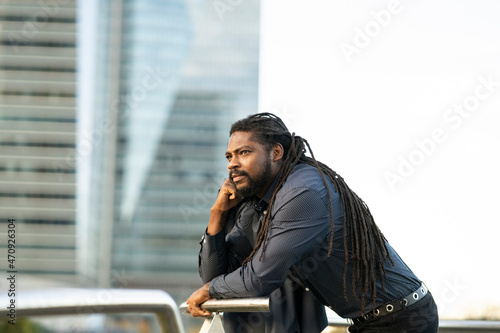 handsome businessman stands leaning on a railing while talking on the phone