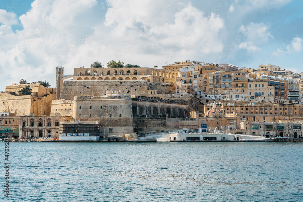 Panoramic view of Valletta,Malta.City skyline from Birgu Vittoriosa harbor.Peaceful cityscape,sunny summer day.Waterfront houses and Upper Barrakka Gardens.Ideal spot for European vacation by sea