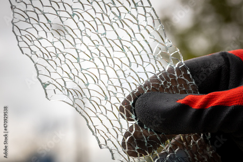 A piece of broken toughened glass held in a hand in a rubber worker glove photo