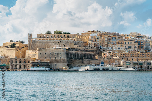 Panoramic view of Valletta,Malta.City skyline from Birgu Vittoriosa harbor.Peaceful cityscape,sunny summer day.Waterfront houses and Upper Barrakka Gardens.Ideal spot for European vacation by sea