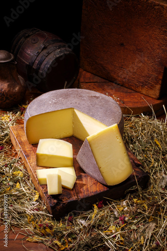 Fototapeta Traditional aged mountain cheese of the Alps offered as loaf and piece at a rust