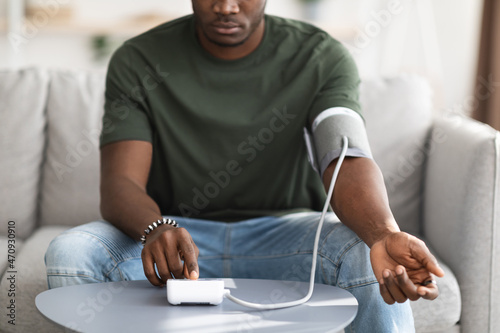 Unrecognizable black man checking blood pressure at home photo