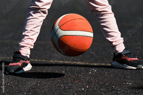 A child is playing basketball outdoors . The girl trains to play on the basketball court .Outdoor training .