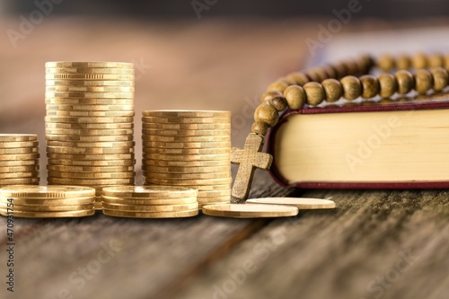 The biblical concept. Golden money on a wooden table with Holy Bible. photo