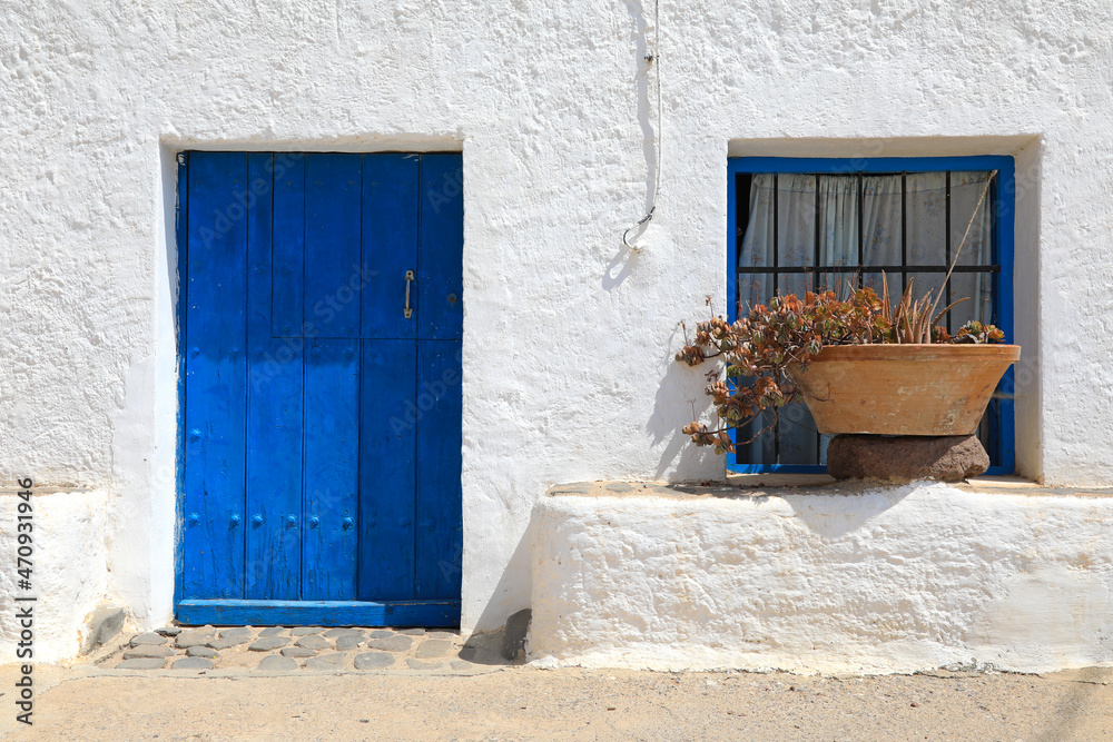 Fototapeta puerta y ventana azul con barrotes y tiesto fachada de casa blanca de pueblo rural mediterráneo almería 4M0A5682-as21