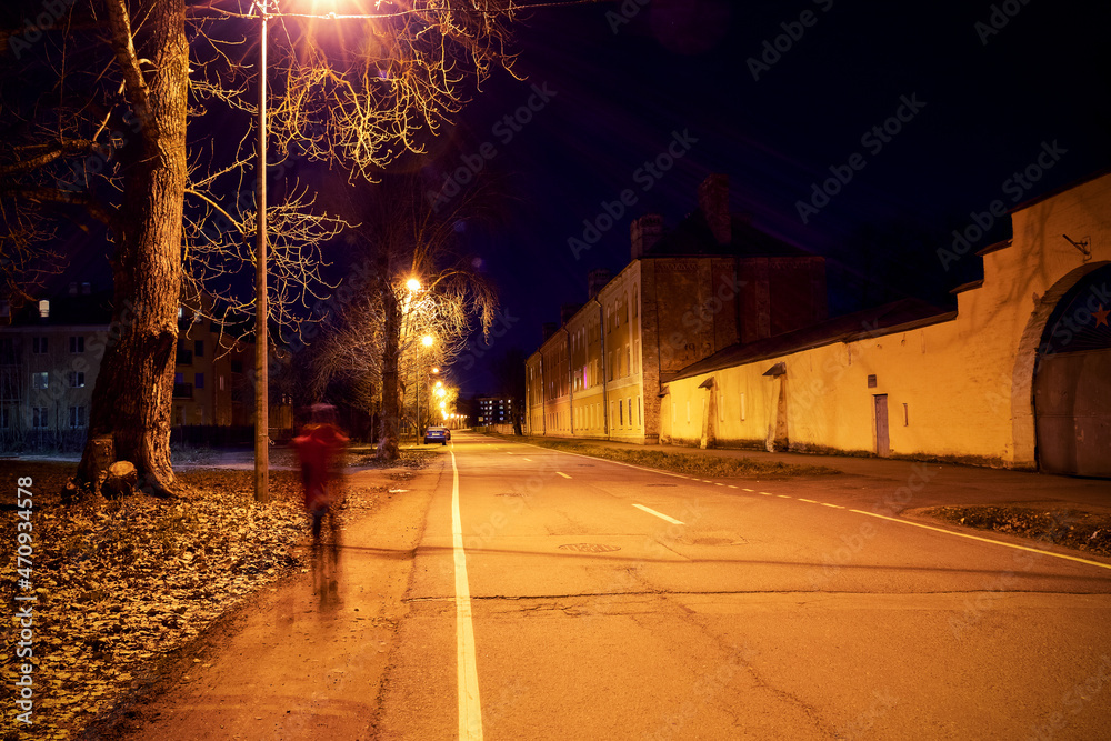 Night city street with blurry walking human, trees and street lights