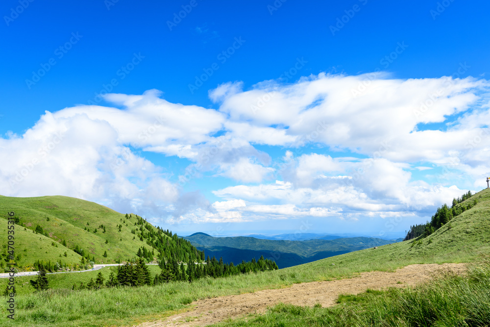 Scenic view over Bucegi Mountains (Muntii Bucegi) in Romania in a sunny summer day with clear blue sky and white clouds.