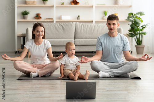 Online Yoga. Happy Young Family With Infant Child Meditating Together With Laptop © Prostock-studio