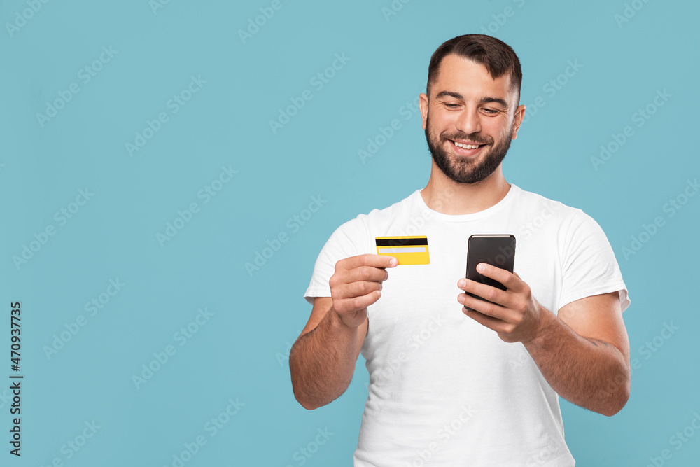 Smiling mature european guy buying goods and paying money using credit card and smartphone Smiling mature european guy buying goods and paying money using credit card and smartphone