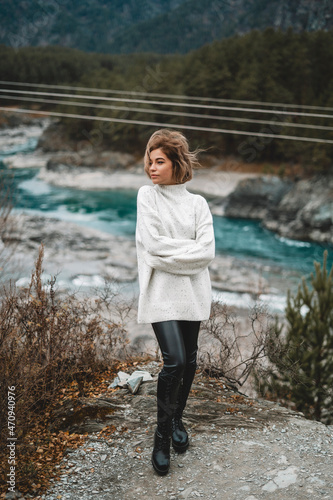 Young woman in mountains river and autumn forest  traveller in beautiful nature. Siberian nature - Altai mountains and turquoise Katun in autumn cloudy evening © Kseniia