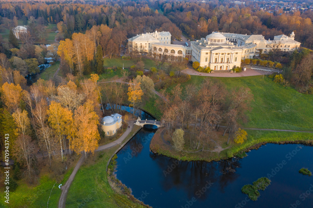 Fototapeta premium Panoramic aerial view of the Pavlovsk Park and the Pavlovsk Palace on an autumn evening.Bright autumn landscape, Slavyanka river,centaur bridge. A suburb of St. Petersburg.
