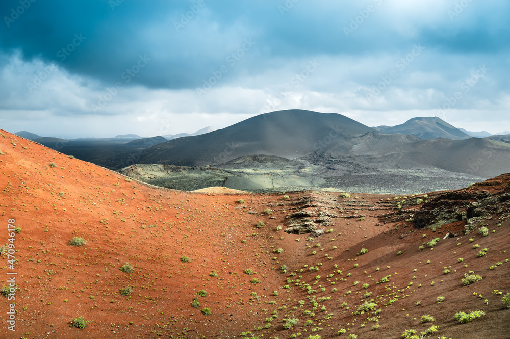 Volcanic landscape in Timanfaya National Park on Lanzarote, Canary Islands, Spain. Dramatic views of volcano craters and desert with black and red lava, ash. Lunar or martian surface