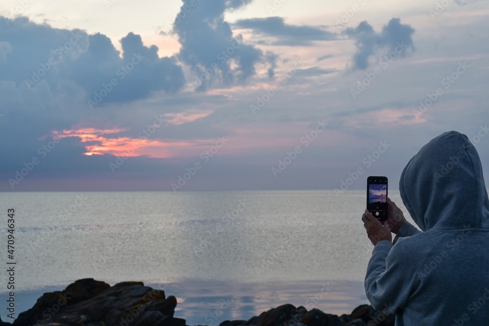 Photo of person photographing sea at sunset
