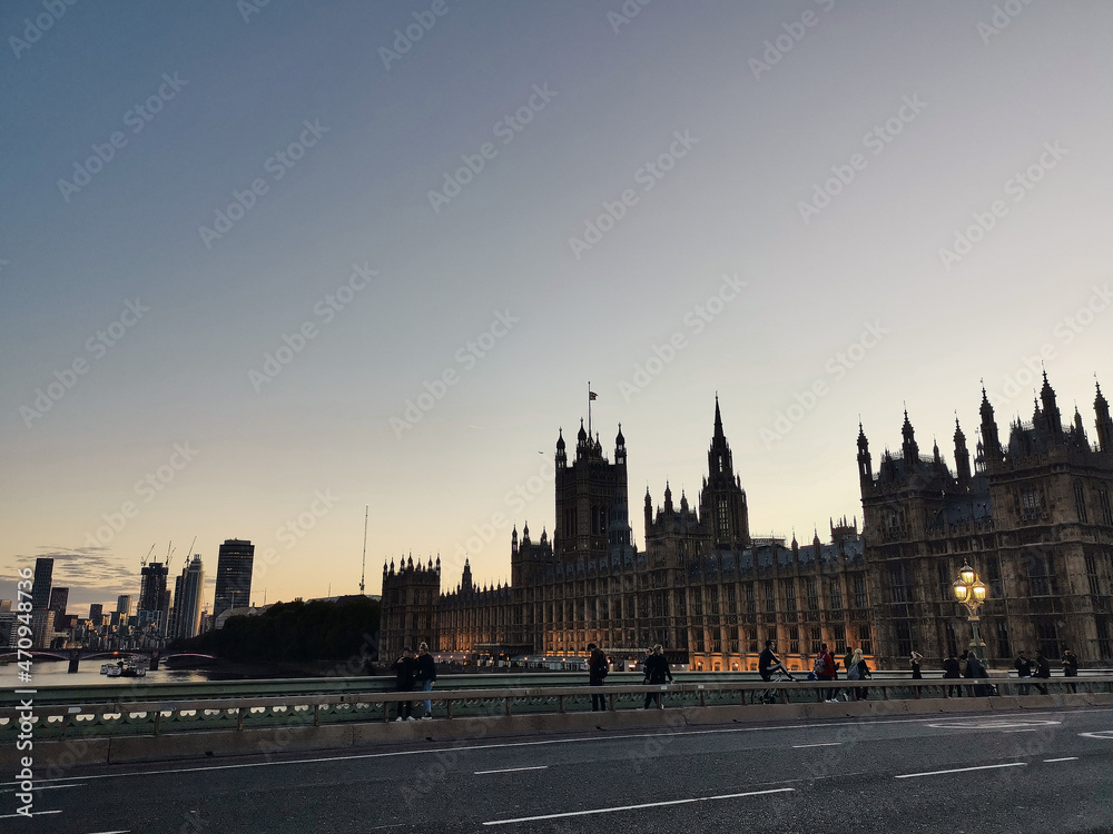 London parliament big ben next to Westminster Abbey at the bridge over river thames by evening sunset warm light