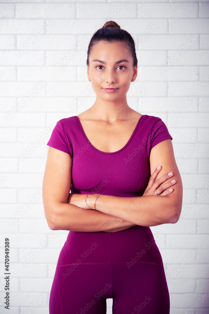 retrato de profesora de yoga y pilates sonriente en un gimnasio con una pesa impartiendo lecciones con ropa violeta en un fondo de pared de ladrillo blanca retrato de profesora de yoga y pilates sonriente en un gimnasio con una pesa impartiendo lecciones con ropa violeta en un fondo de pared de ladrillo blanca