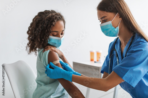 Medical Worker Vaccinating Black Pre-Adolescent Girl Making Vaccination In Clinic