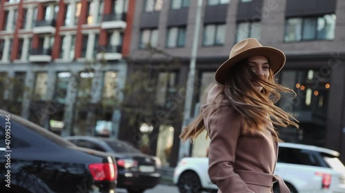 Happy long hair woman in a coat and hat turn around and look at camera