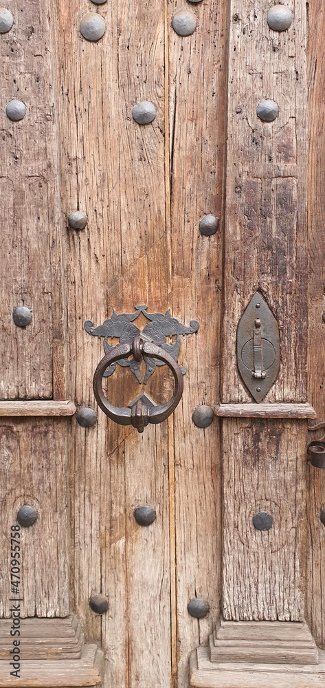 Dilapidated old wooden door with rusty fittings and a metal knocker. Dilapidated old wooden door with rusty fittings and a metal knocker.