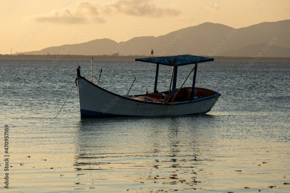 boat on the calm waters of the sea in the afternoon of a beautiful sunset, in the background, yellow and orange sky