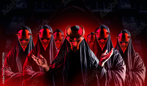 Scary horror occult sectarians with preacher wearing black hood and metal masks on black background with red glow. photo