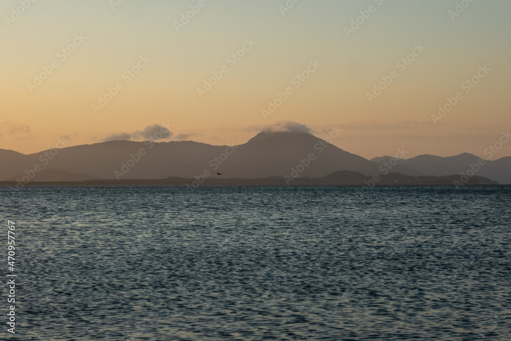 beautiful landscape of the sea at the end of the afternoon, in the background beautiful mountains and sky at sunset