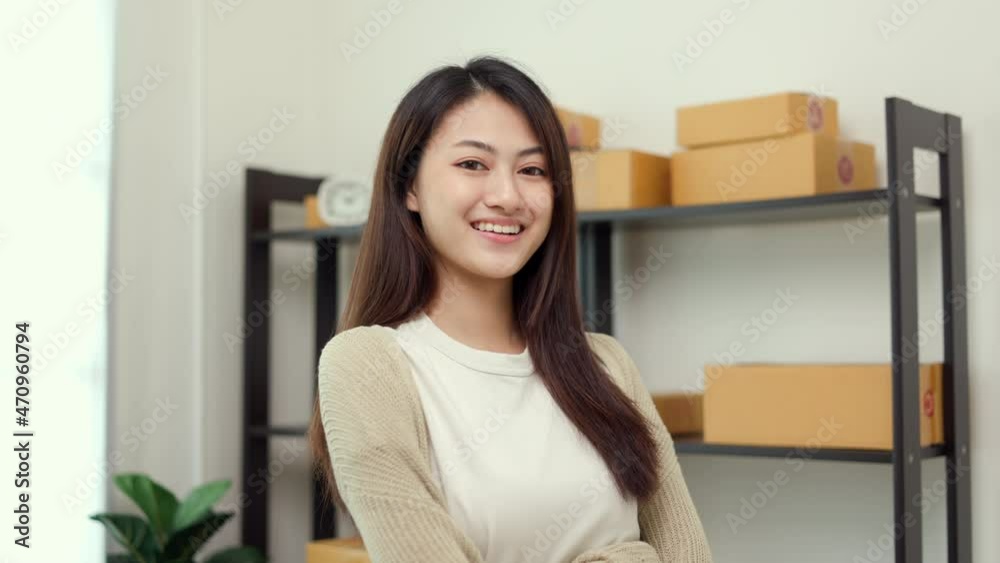 Beautiful young asian entrepreneur standing pose smiling to camera. Female small Business owner working at home. Startup freelance people with many parcel on background. Beautiful young asian entrepreneur standing pose smiling to camera. Female small Business owner working at home. Startup freelance people with many parcel on background.
