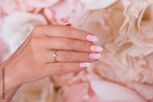 Female hand with ombre manicure nails  pink gel polish  on paper flowers background