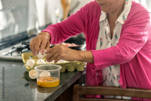 Latin Grandma breaking eggs for breakfast at her kitchen
