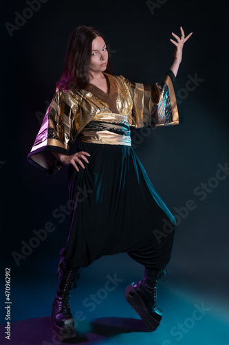 Stylish and daring image, futuristic fashion. A young woman in a multicultural outfit mixing Asian and European style. Stylish brunette posing pathetically, photo in the studio on black photo