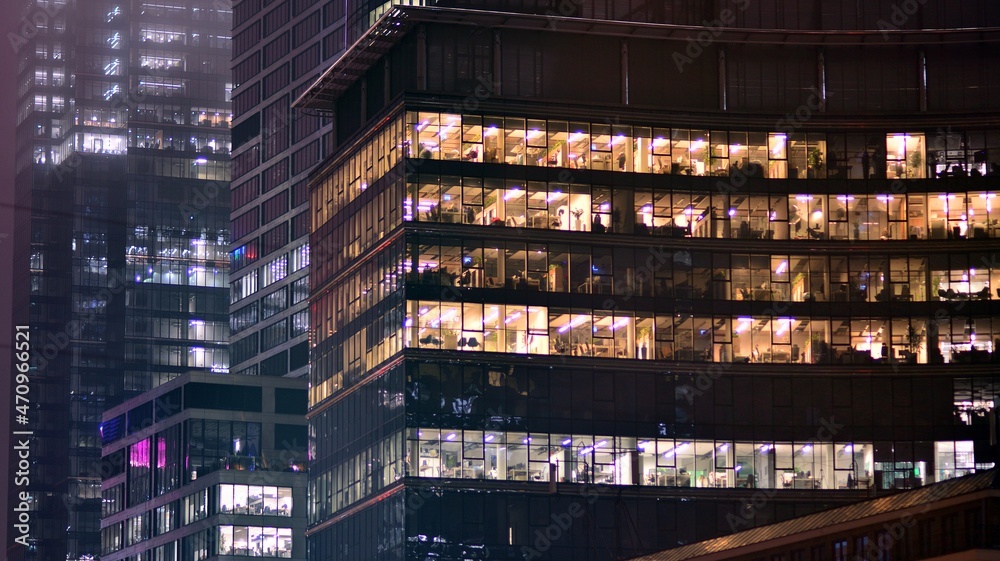 Corporate building at night - business concept. Glass wall office building .Modern office windows of skyscraper glowing at night.