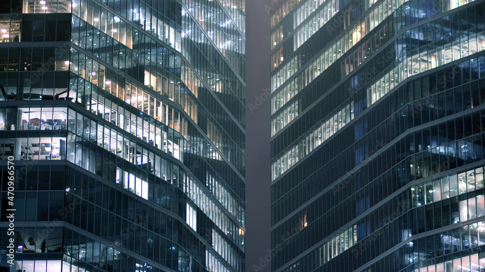 Obraz premium Corporate building at night - business concept. Glass wall office building .Modern office windows of skyscraper glowing at night.
